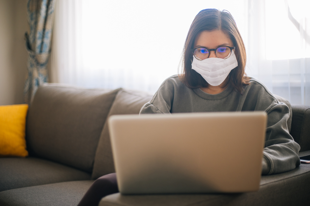 Young woman working from home wearing protective mask