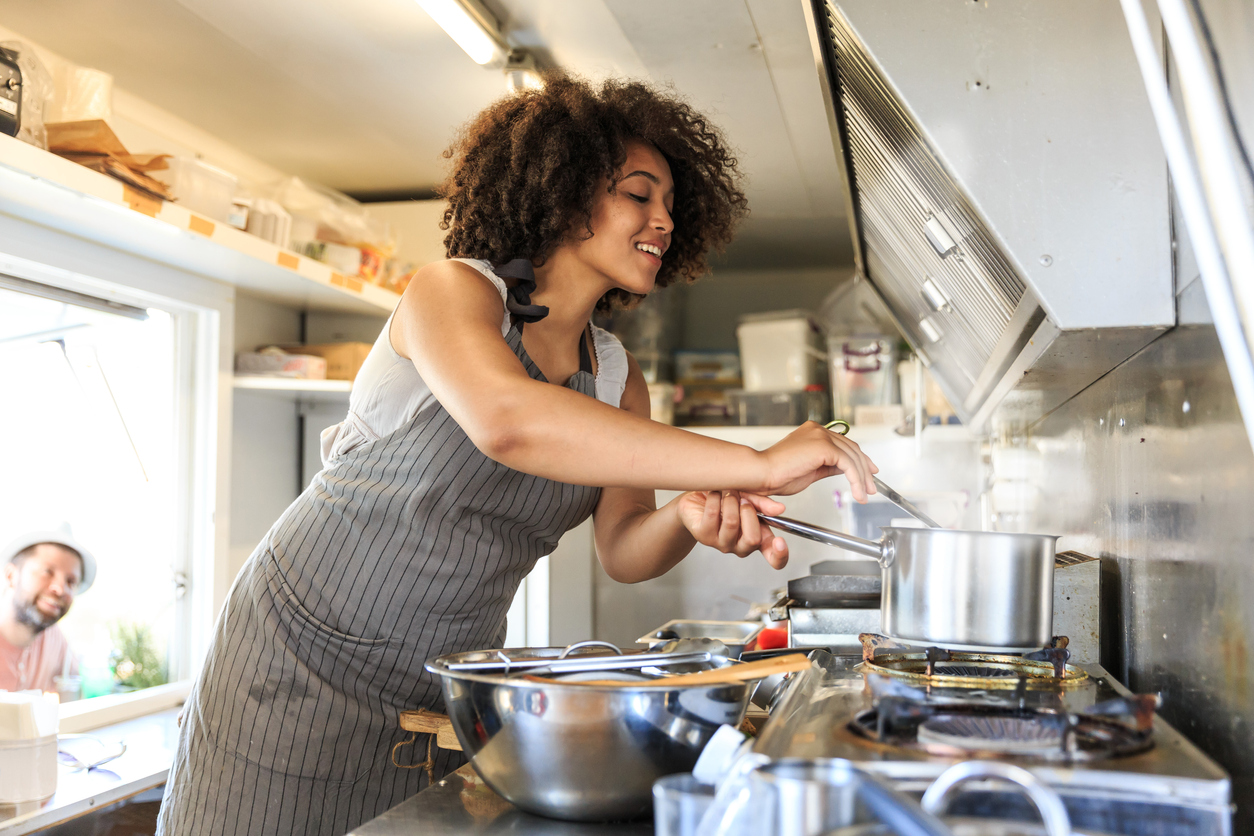 Smiling food truck worker cooking inside of a van.