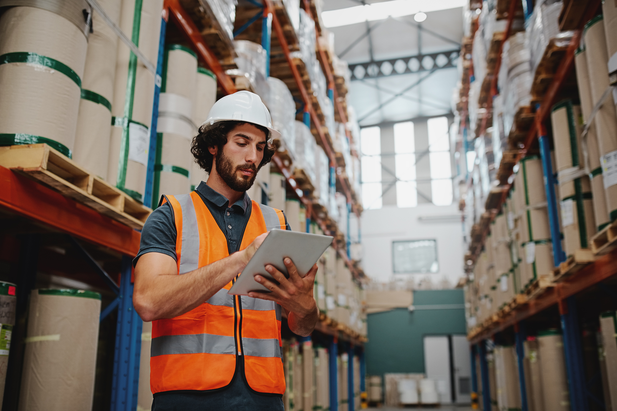Deskless worker in hard hat using a tablet in a manufacturing facility