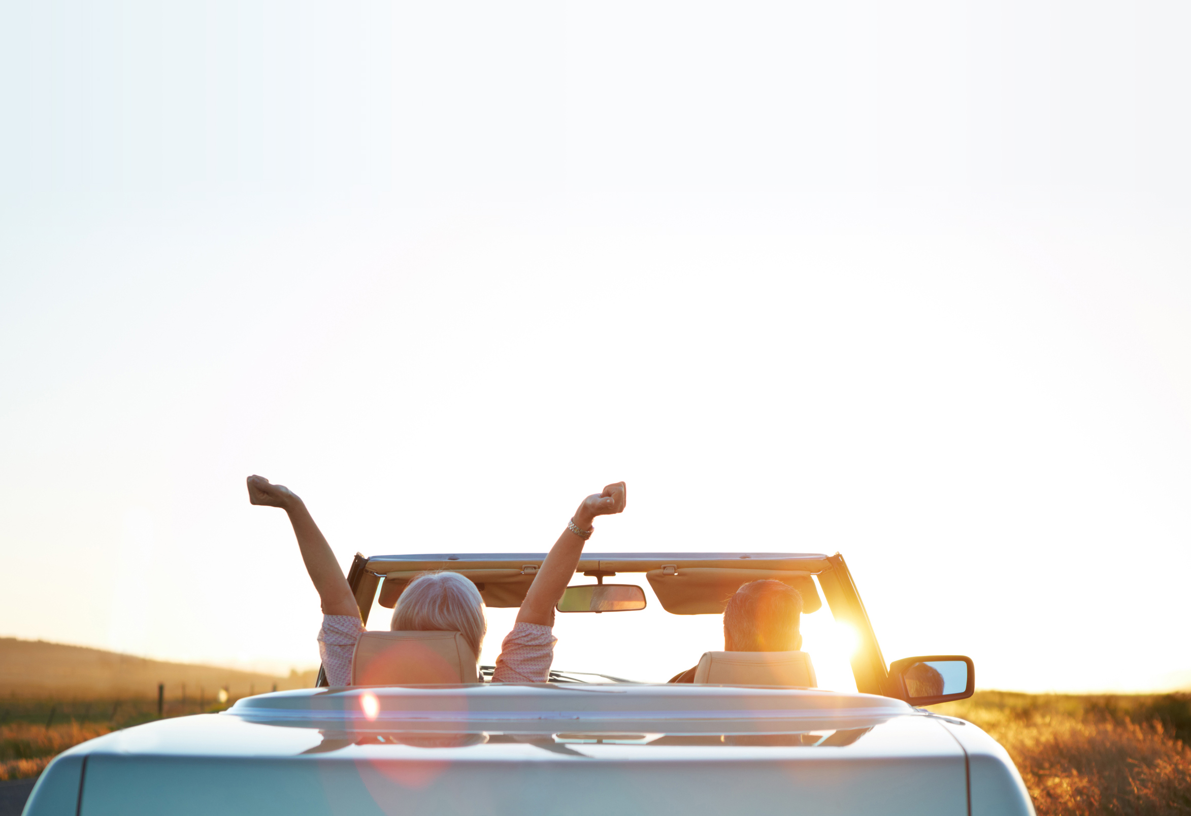 Couple driving a car on an open road, representing retirement freedom